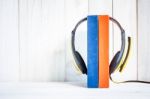 Headphones On Books On White Wood Background Stock Photo