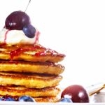 Pile Of Pancakes With Blueberries, Cherries And Sour Cream Stock Photo