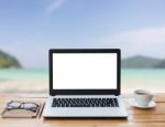 Laptop Computer And Coffee On Wood Workspace And The Beach Background Stock Photo