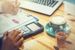 Business Man Sitting On A Calculator To Figure Out In A Coffee S Stock Photo