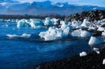 Pieces Of Ice On The Black Sand Beach In Iceland, With A Big Mountain Covered With Snow As A Background Stock Photo