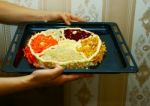 Woman Is Holding A Baking Sheet With A Salad In The Form Of Cake Stock Photo