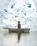 Boy Standing On An Old Wooden Rowboat In The Sea Stock Photo