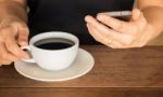 Hand On Coffee Cup And Smartphone Stock Photo