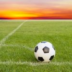 Soccer Ball On Soccer Field Against Sunset Sky Stock Photo