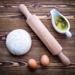 Raw Pizza Dough And Rolling Pin On Wooden Background Stock Photo