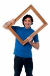 Smiling Guy Looking Through Picture Frame Stock Photo