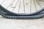 Bicycle Wheel With Flat Tyre On The Concrete Road Stock Photo