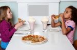 Little Girls Enjoying Pizza In A Restaurant Stock Photo