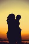 Silhouette Of Mother And Child Enjoying The View At Riverside Stock Photo