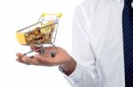 Man Holding A Shopping Cart Filled With Gold Coins Stock Photo