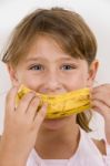 Little Girl Eating Banana Stock Photo