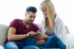 Beautiful Young Couple Using Mobile Phone At Home Stock Photo