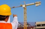 Young Engineer In Orange Shirt Stands Pointing At A Building Bei Stock Photo