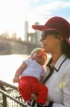 Mom Is Holding Her Baby With The City In The Background Stock Photo