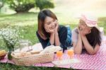 Two Asian Girlfriends Lying On The Lawn, Women In Park During Th Stock Photo