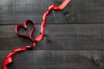 Red Ribbon In Heart Shape On Wooden Background Stock Photo