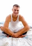 Young Man Sitting On Bed Stock Photo