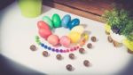 A Few Colorful Easter Eggs As A Flower Shape With Candies And Chocolate And Garden Plants Over Wood Background Left Side View Happy Easter Stock Photo