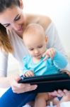 Mother And Baby Girl Using Digital Tablet At Home Stock Photo