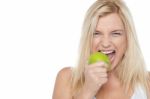 Closeup Shot Of A Blonde Woman Biting An Apple Stock Photo