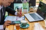 Business Man Sitting On A Calculator To Figure Out In A Coffee S Stock Photo