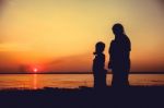 Silhouette Of Mother And Child Enjoying The View At Riverside Stock Photo