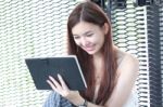 Portrait Of Thai Adult Beautiful Girl Using Her Tablet And Smile In University Stock Photo