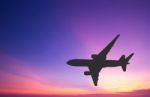 Silhouetted Commercial Airplane Flying At Sunset Stock Photo