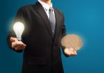 Light Bulb And Brain In The Hands Of Businessmen Stock Photo