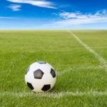 Soccer Ball On Soccer Field Against Blue Sky Stock Photo