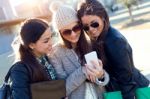 Three Students Girls Using Mobile Phone In The Campus Stock Photo