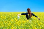 Young Woman Standing In Yellow Rapeseed Field Stock Photo