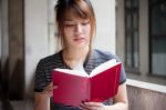 Portrait Of Thai Adult Beautiful Girl Reading Red Book Stock Photo