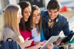 Students Having Fun With Smartphones And Tablets After Class Stock Photo