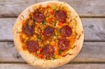 Delicious Baked Salami Pizza Served On Rustic Wooden Table Stock Photo