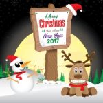 Snowman And Reindeer With Wooden Sign In Winter On Night Sky Background. Merry Christmas And Happy New Year On Wooden Sign Stock Photo