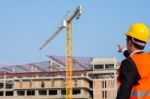 Young Engineer In Orange Shirt Stands Pointing At A Building Bei Stock Photo