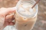 Hand On Glass Of Iced Milk Coffee With Vintage Filter Effect Stock Photo