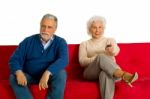 Elderly Couple Sitting In Sofa Stock Photo