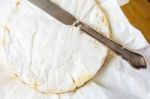 Camembert Cheese Wrapped In Paper With Vintage Knife On Wooden T Stock Photo