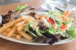 Delicious Barbecued Ribs With Spicy Sauce And Organic Salad Stock Photo