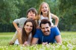 Happy Young Family Lying On Grass Stock Photo