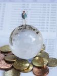 Miniature Businessman Stand On Globe Of Glass, Euro Coins And Bo Stock Photo