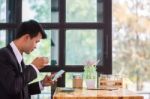 Young Businessmen Are Looking At Mobile Phones And Holding A Cup Stock Photo