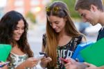 A Group Of Students Having Fun With Smartphones After Class Stock Photo