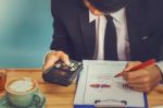 Business Man Sitting On A Calculator To Figure Out In A Coffee S Stock Photo