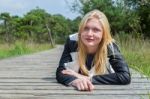 Blonde Girl Lying On Wooden Path In Nature Stock Photo