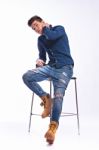 Male Model In Denim Jeans Sitting On A Chair . Studio Shoot Stock Photo