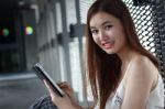 Portrait Of Thai Adult Beautiful Girl Using Her Tablet And Smile In University Stock Photo